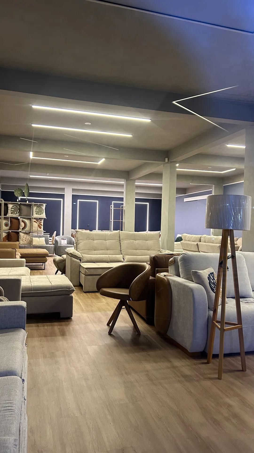 Composição de sofás bege, poltrona giratória de couro e luminária de piso em ambientação de sala no showroom da Art's Colchões, Ingleses Florianópolis